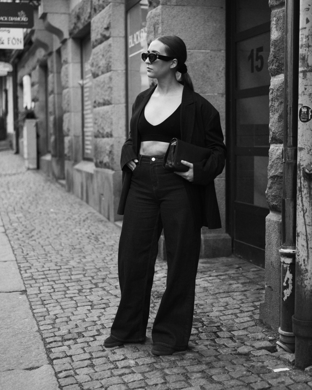 Woman wearing the BAUME Deep V Bralette with jeans and a blazer, styled with sneakers, sunglasses and a bag for an elevated everyday outfit.