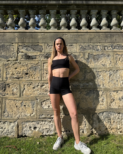 Woman wearing the BAUME Form Bralette and Form Shorts in a green park. Natural fiber athleisure crafted from TENCEL™ Lyocell with OEKO-TEX® certified materials, designed for everyday movement and comfort.