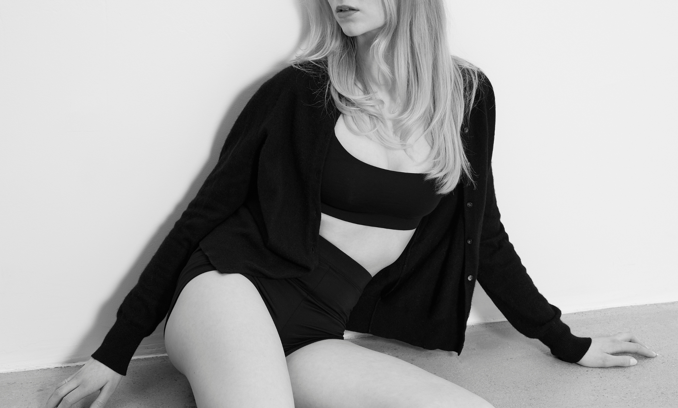 Woman sitting on the floor wearing a Baume Essentials TENCEL™ Lyocell bralette and shorts set, styled as eco-friendly everyday intimates with soft, breathable fabric in a minimalist studio.