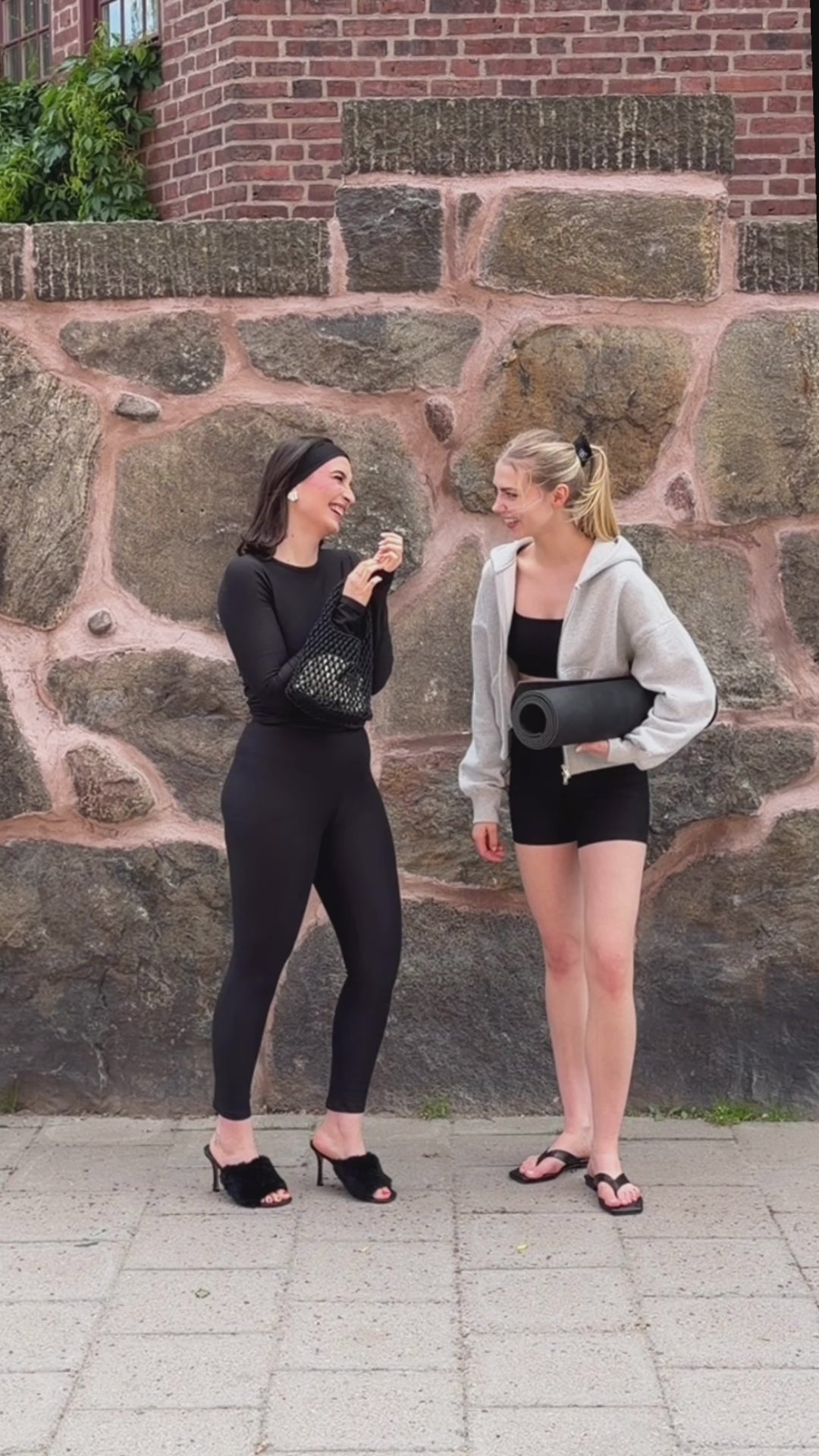 Two women wearing BAUME Form black tights, long-sleeve top, bralette and shorts, styled from elevated with heels and accessories to relaxed with a hoodie and flip flops.
