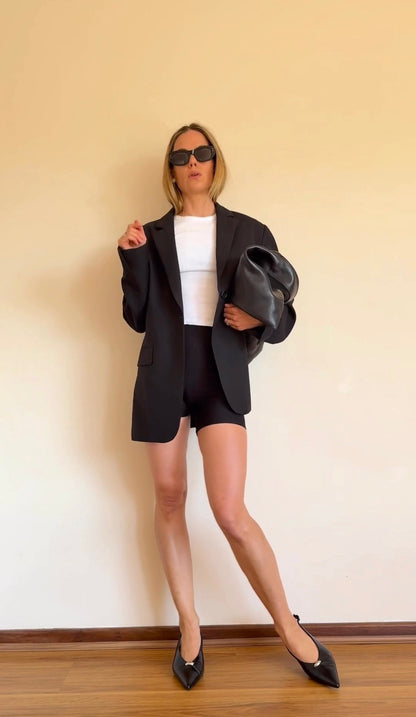 Woman wearing BAUME Form Bralette and Shorts with a T-shirt, blazer and heels, showing versatile activewear styled for an elevated workwear look.